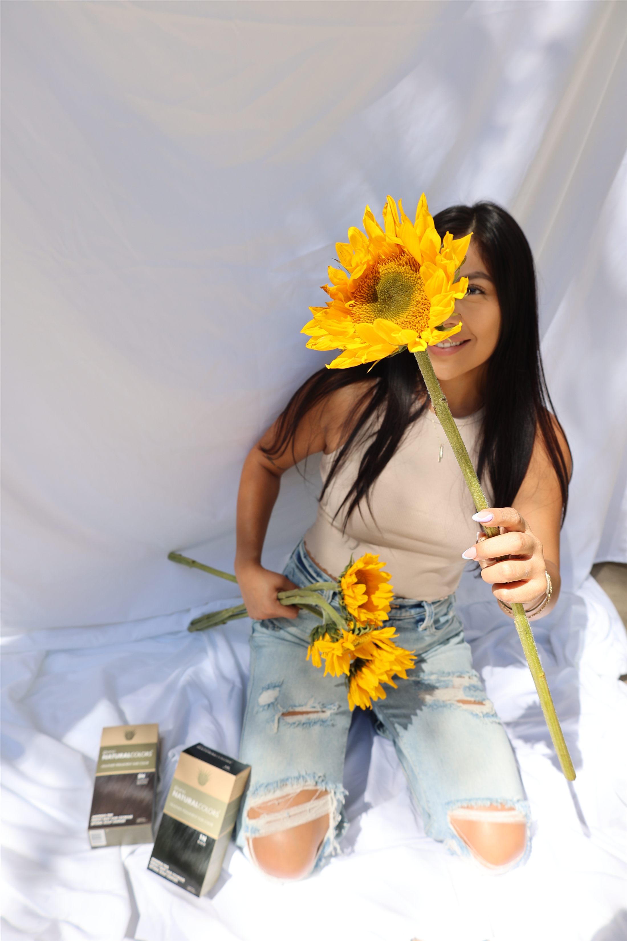 Model holding a sunflower toward the camera
